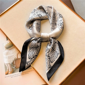Macro view of black and white paisley silk scarf with baroque patterns on display board