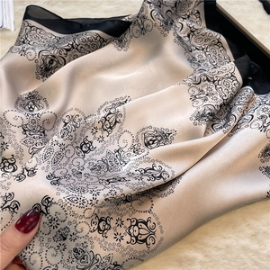 Detail showing paisley pattern on silky square scarf with champagne and black borders