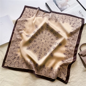 Close-up of baroque floral silk scarf with elegant satin sheen on a textured white rug