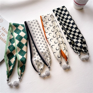 Détail de quatre foulards en soie à motifs avec d'élégants pendentifs boule strass aimanté