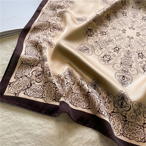 Detailed view of champagne gold satin scarf with vintage brown floral patterns on plush