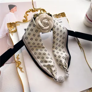Détail d'un foulard en soie à motifs de losanges avec décoration de fleur de camélia