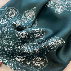 Macro shot of dark green paisley silk scarf showing soft satin luster and elegant drapes