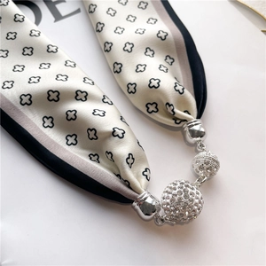 Détail d'un collier écharpe en soie à motif trèfle avec des pendentifs en strass brillants