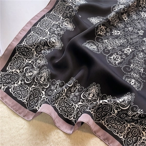 Close-up of black silk scarf with paisley pattern on soft beige plush background