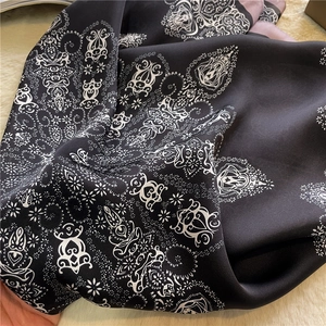 Macro shot of paisley floral pattern on black silk scarf with soft gloss texture