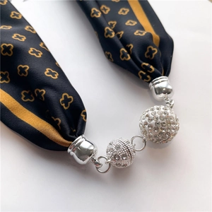 Gros plan détaillé d'un collier écharpe en soie avec des pendentifs sphériques ornés de strass