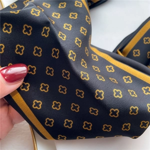 Gros plan détaillé d'un foulard en soie noir avec motif trèfle doré et bordure rayée
