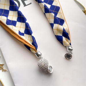 Gros plan d'un foulard en soie à losanges bleus avec un fermoir boule en strass aimanté