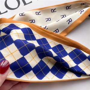 Détail d'un foulard en soie double face avec motifs à carreaux bleus et bords orangés