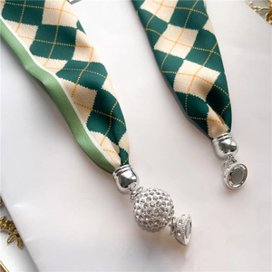 Détail d'un foulard en soie à carreaux verts avec breloque boule sertie de strass