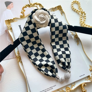 Détail de l'écharpe en soie à damier avec fleur de camélia et pendentifs en cristal