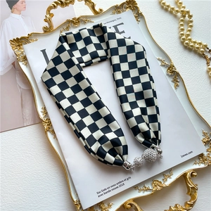 Détail d'un foulard en soie à damier avec un pendentif boule en strass sur un magazine