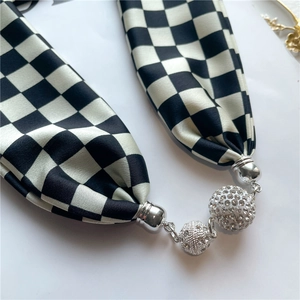 Détail macro d'un foulard en satin à damier avec un pendentif boule en strass brillant