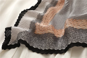 Gros plan sur un foulard en soie plissée avec des motifs géométriques ondulés
