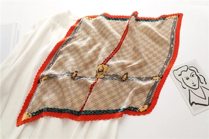 Détail d'un foulard plissé aspect soie avec motif équestre et bordure rouge ondulée