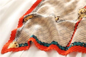 Vue détaillée du foulard plissé en soie avec bordure orange et imprimé équestre