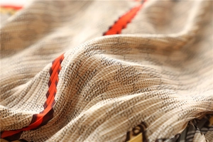 Vue macro du foulard en soie plissé avec motifs géométriques et bordures rayées