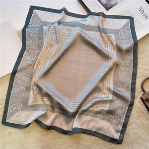 Foulard di seta a righe con motivo geometrico grigio su un tappeto beige