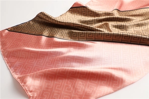 Detail of satin silk scarf showing Greek Key geometric pattern and pink gold patchwork