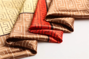 Close-up of satin scarf featuring classic Greek Key patterns in orange and coffee tones