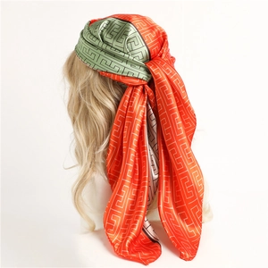 Detail of satin headscarf featuring orange and green Greek Key geometric patterns