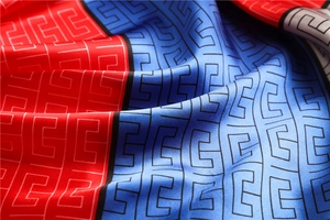 Detail of red and blue satin scarf with black geometric patterns and silky texture