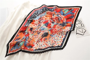 Dettaglio di un foulard di seta plissettato con motivi astratti su camicia bianca