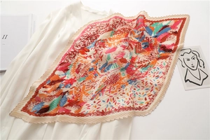 Dettaglio di sciarpa in seta a pieghe con stampe colorate e bordo ondulato
