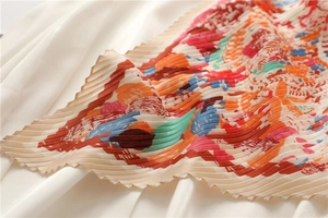 Dettaglio macro della sciarpa in seta plissettata multicolore con stampe astratte arancioni