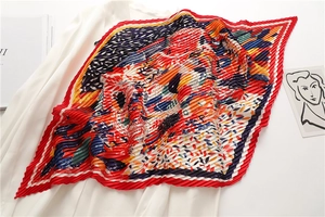 Dettaglio del foulard a pieghe arancione con stampa artistica astratta e bordo rosso
