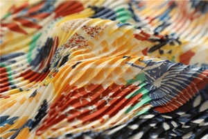 Dettaglio macro dello foulard in seta a pieghe con motivo astratto arancio e blu