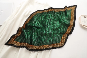 Detail of dark green pleated silk scarf with leopard print edge on white clothing