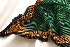 Detailed macro view of green pleated scarf with leopard print edge and floral texture