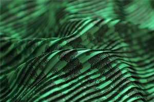 Close-up of pleated emerald green silk scarf with delicate black floral and lace patterns