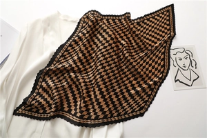 Detail of pleated silk scarf with brown and black houndstooth pattern on white shirt
