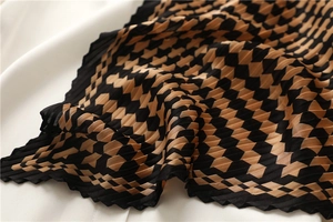 Detail of pleated black and orange checkerboard scarf with crinkled texture and zigzag edges