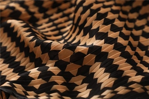 Macro detail of pleated black and khaki geometric diamond pattern on silky neckerchief