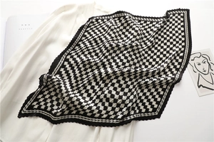 Detail of black and white geometric checkerboard scarf with pleated texture on white shirt