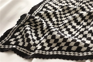 Macro detail of black and white checkered pleated silk scarf with fine texture