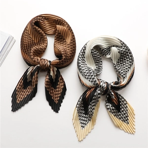 Detail of pleated geometric scarves in brown and beige with black houndstooth pattern
