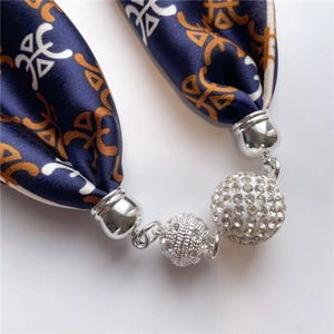 Dettagli di sfere di strass scintillanti e sciarpa in seta blu navy con motivi geometrici