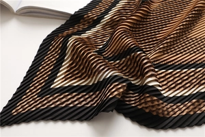 Detailed view of accordion pleats on geometric checkered silk scarf in earth tones