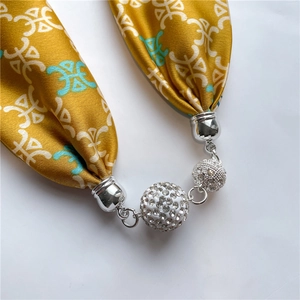 Macro di una collana foulard in seta con pendente a sfera di cristallo e dettagli argento