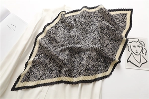 Detail showing the pleated texture and geometric pattern of the black and white scarf