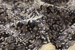 Macro detail of pleated scarf showing black and white geometric pattern and texture