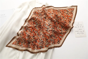 Detail of pleated silk scarf with orange and brown geometric patterns and wavy edges