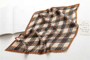 Close-up of pleated retro houndstooth scarf with brown and green geometric texture