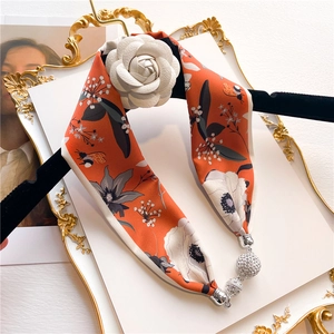 Detail of orange floral silk scarf necklace featuring white camellia and diamond pendants