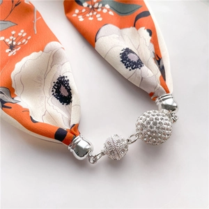 Macro detail of silk scarf necklace featuring floral print and sparkling rhinestone beads